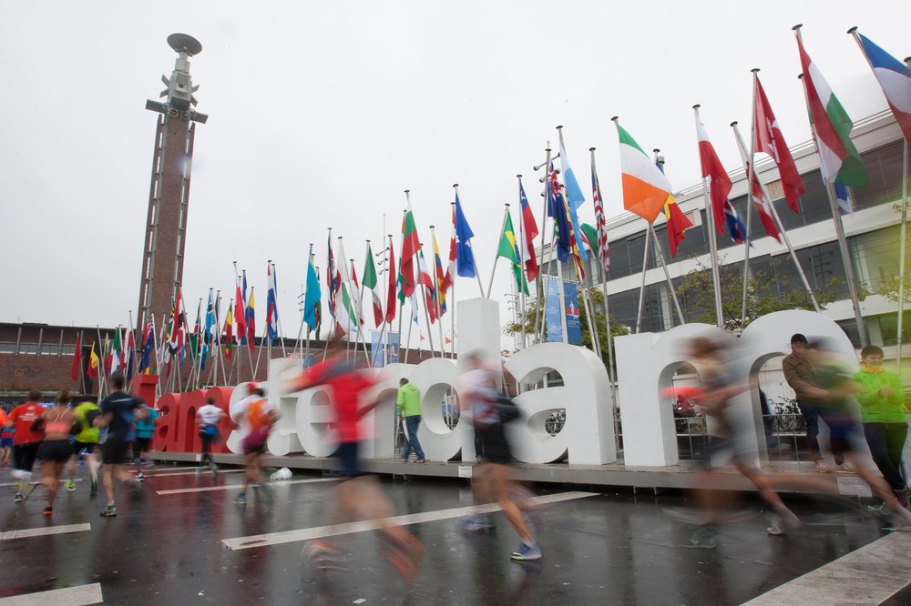 A picture of a group of runners passing the Amsterdam sign.