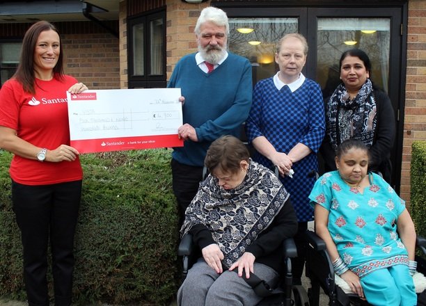 A picture of a Santander employee, the Residential Manager and residents with the cheque.