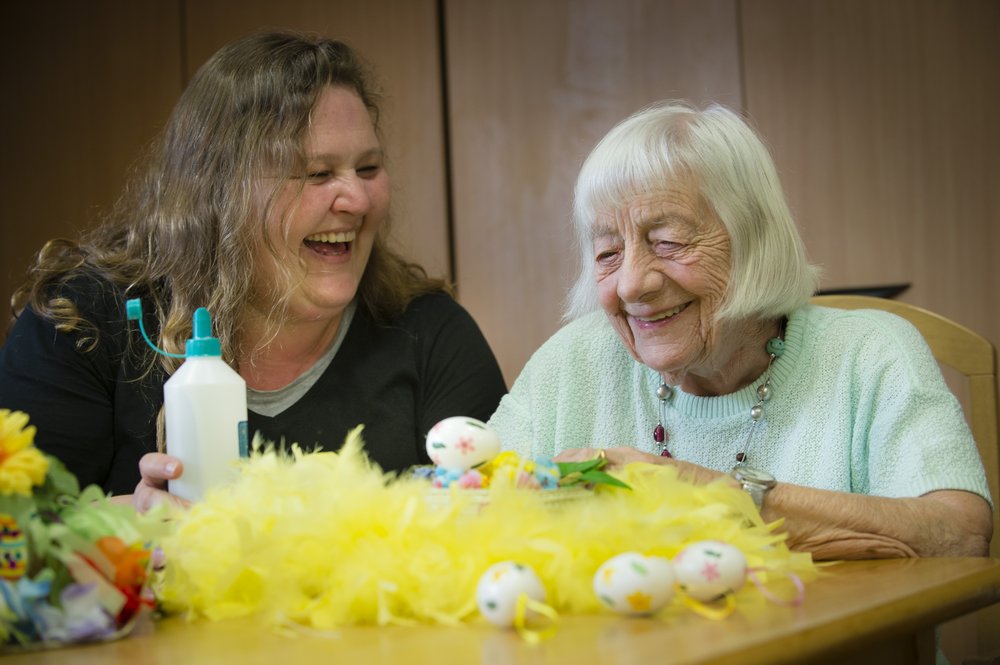 A picture of a care assistant and resident taking part in an activity