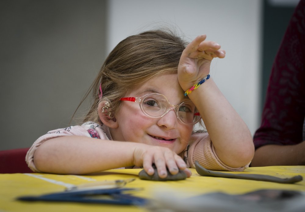 A picture of little girl wearing glasses, taking part in a children's craft activity.