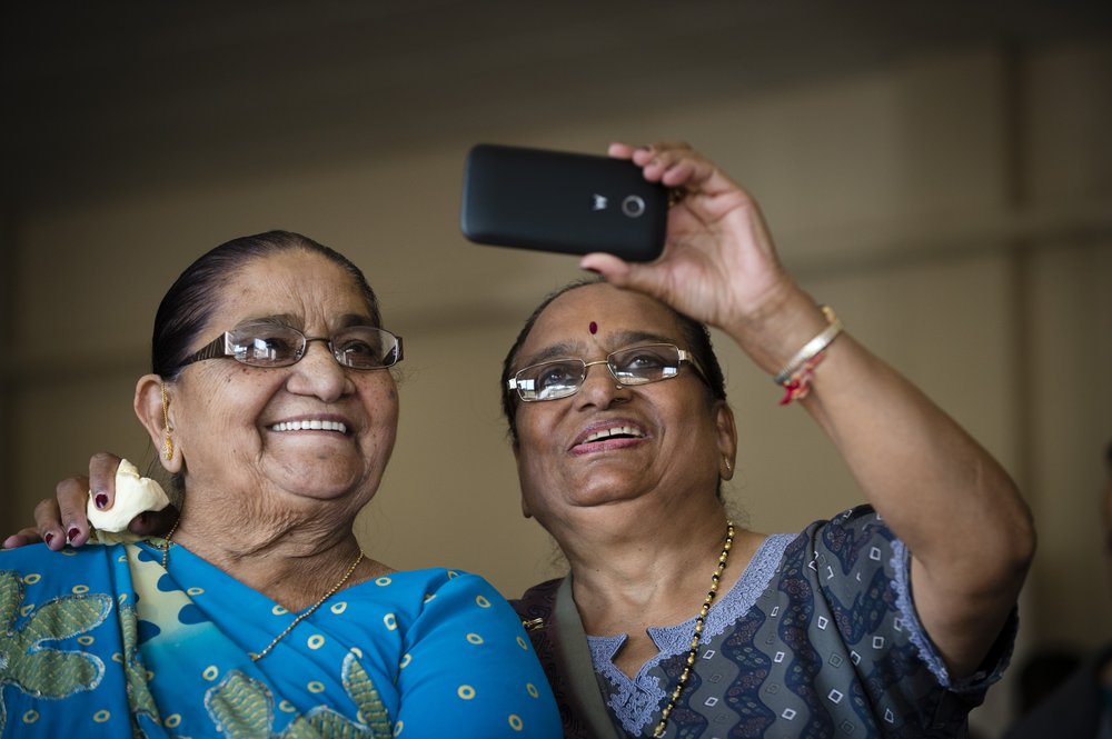 A picture of two ladies smiling and looking through a camera phone.