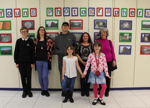 A picture of children, young people and their family stood in front of the photo exhibition.