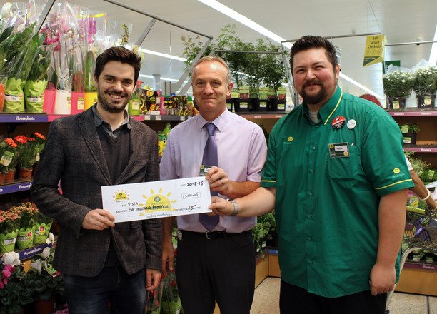 A picture of Chris Anderson and two Morrisons employees holding the cheque.