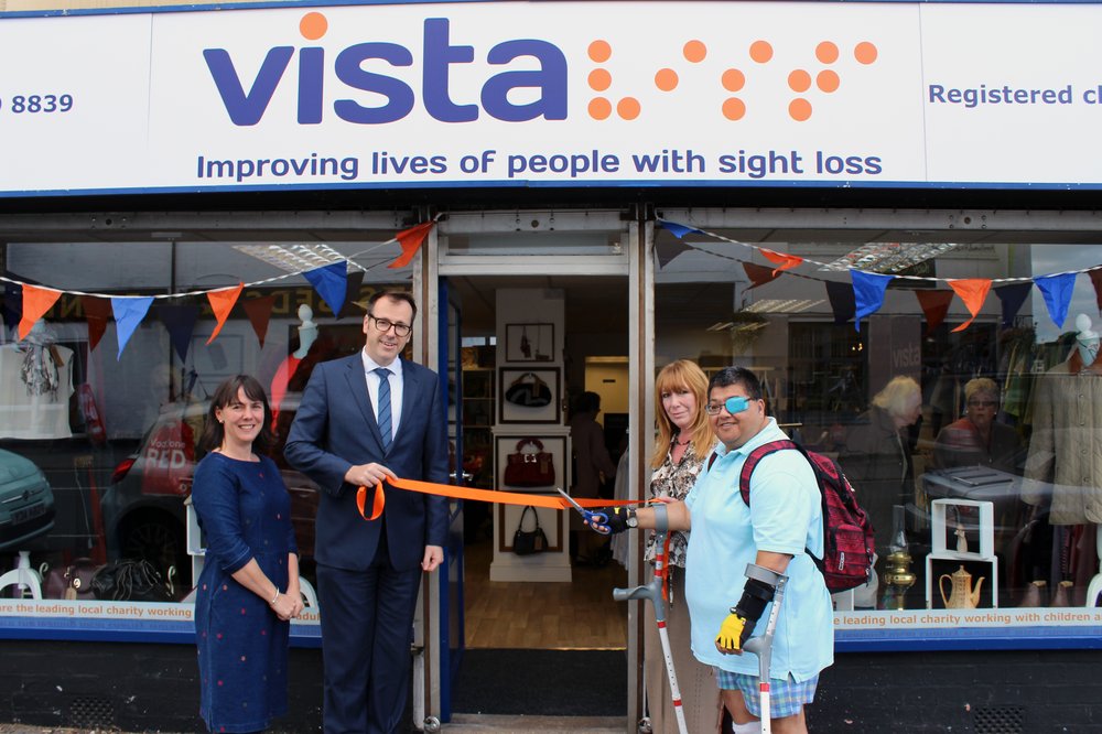 A picture of Vista staff and a service user cutting the ribbon to open the charity shop.