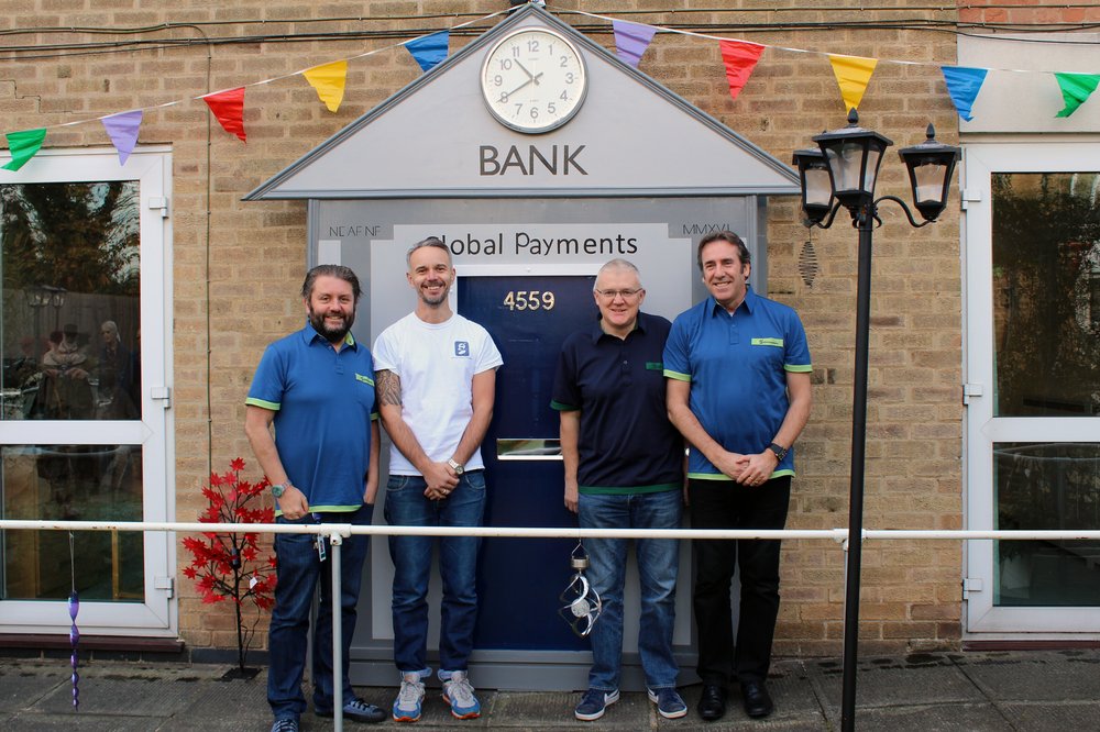 A picture of the Global Payments team in front of the mock bank in the sensory garden.