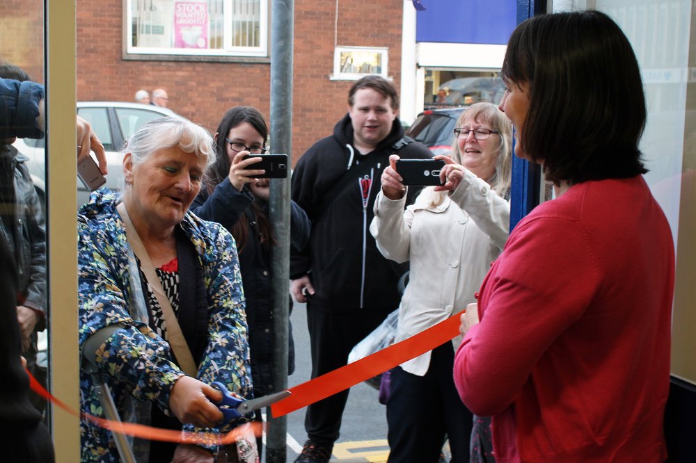 A picture of a lady cutting the ribbon to open the Wigston charity shop.