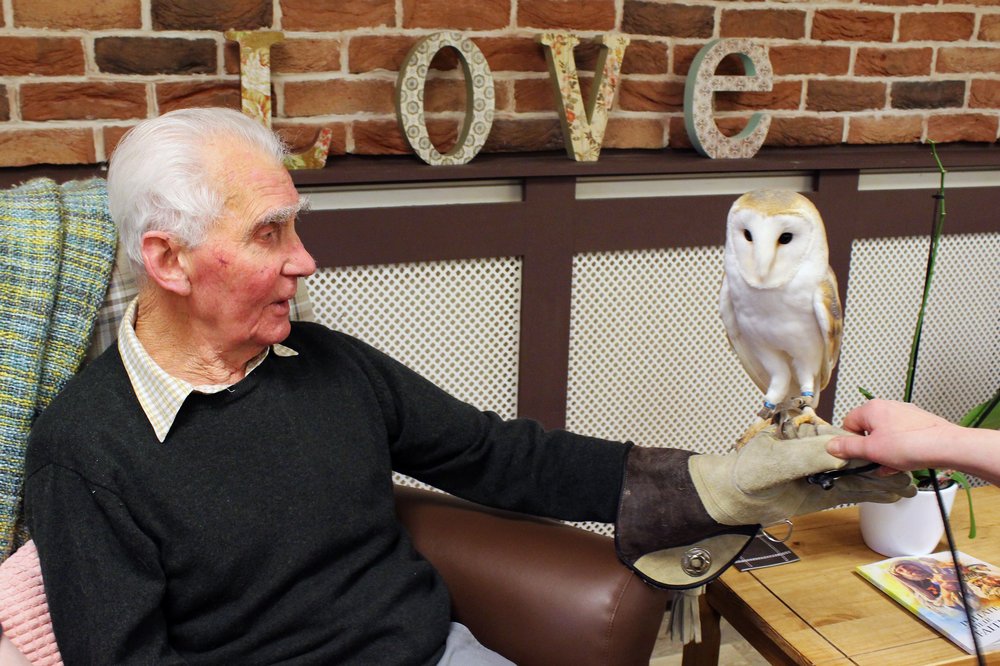 A picture of a resident holding an owl on his hand.