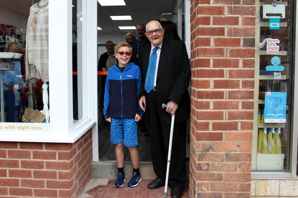 A picture of a young boy and an older gentleman, supported by Vista, stood in front of the new Rothley shop.