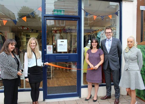 A picture of Vista staff cutting an orange ribbon in front of the Loughborough charity shop.