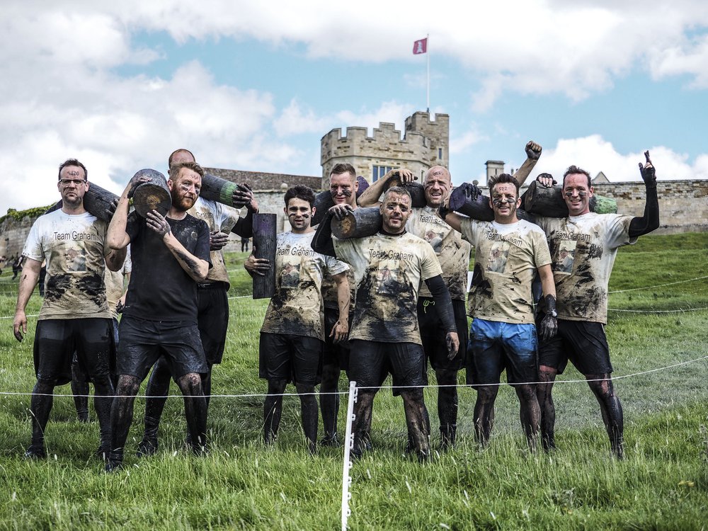 A picture of a group who have taken part in the race, covered in mud and cheering.