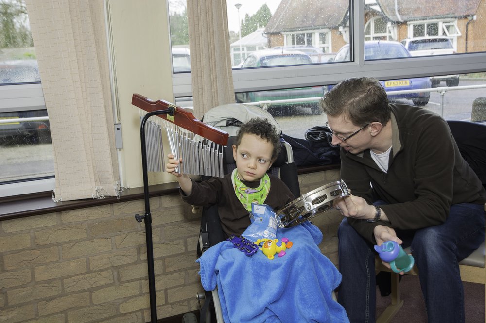 A picture of a boy playing an instrument in a music therapy session.