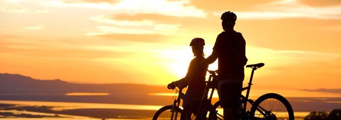 A picture of two cyclists with the sunset behind them.