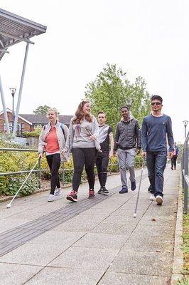 A group of prospective students with canes walking down a paved path.