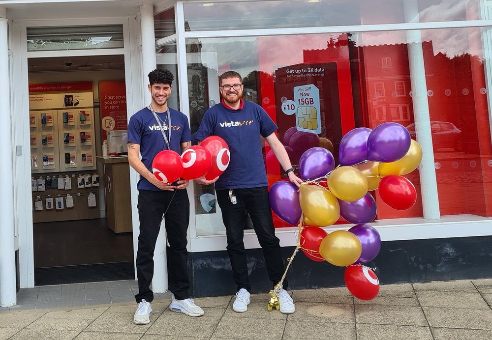 Image shows members of staff at Fone Booth with blue and orange balloons.