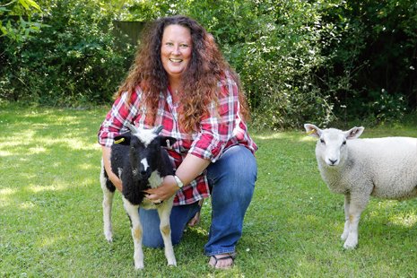 [Image Description: Image of Beth knelt with her a young goat and lamb, two of the  animals she has looked after alongside a menagerie of rescue animals]]