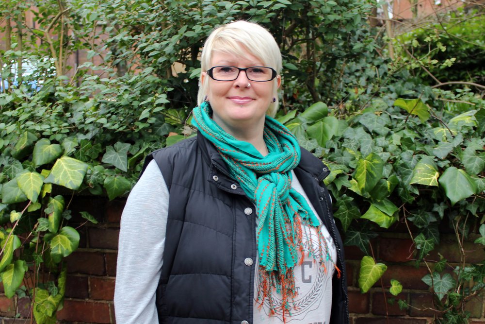 A picture of Cath stood in front of greenery.