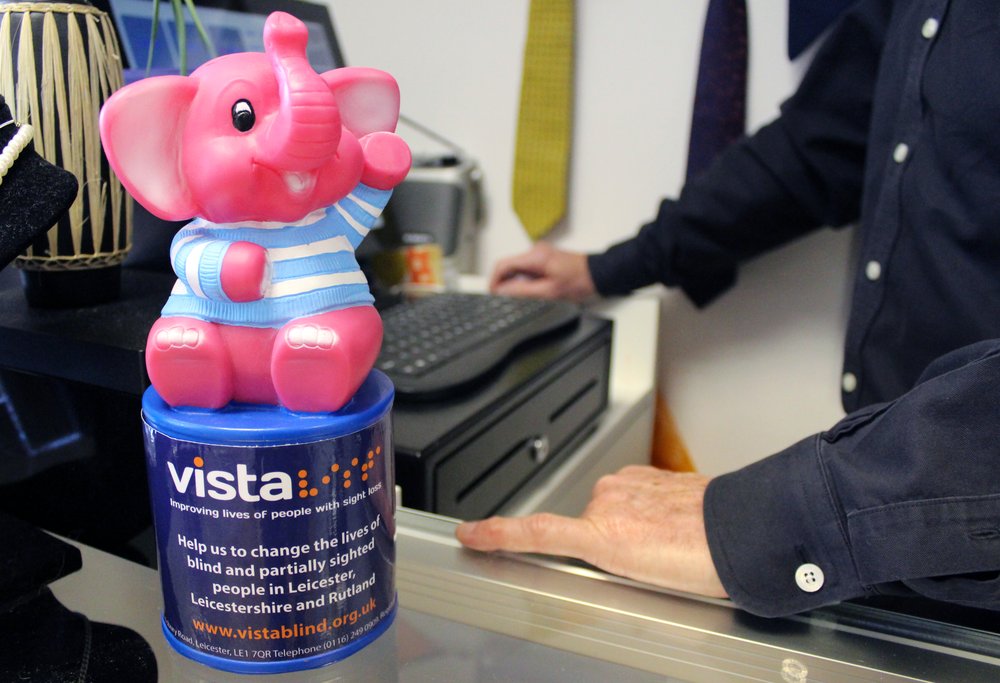 A picture of a Vista pink elephant collection box on a shop counter.