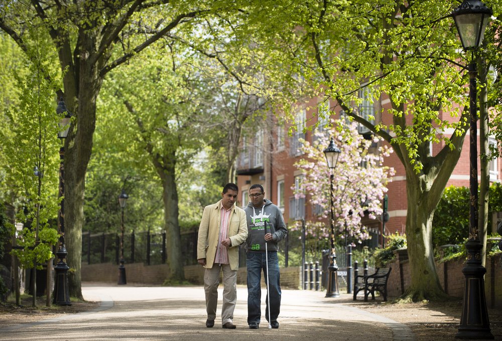 A picture of two males, one with a cane, walking together along New Walk in Leicester.