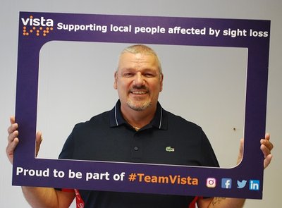 Image is of Steve Payne, Vista's Director of Care and Services holding a Vista branded selfie frame that says 'Proud to be part of #TeamVista'
