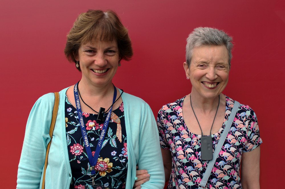 A picture of a Vista Guide Communicator and Lynda, linking arms and smiling.