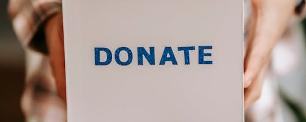 [Image Description: Image of somebody holding a box with the text 'Donate' on it]