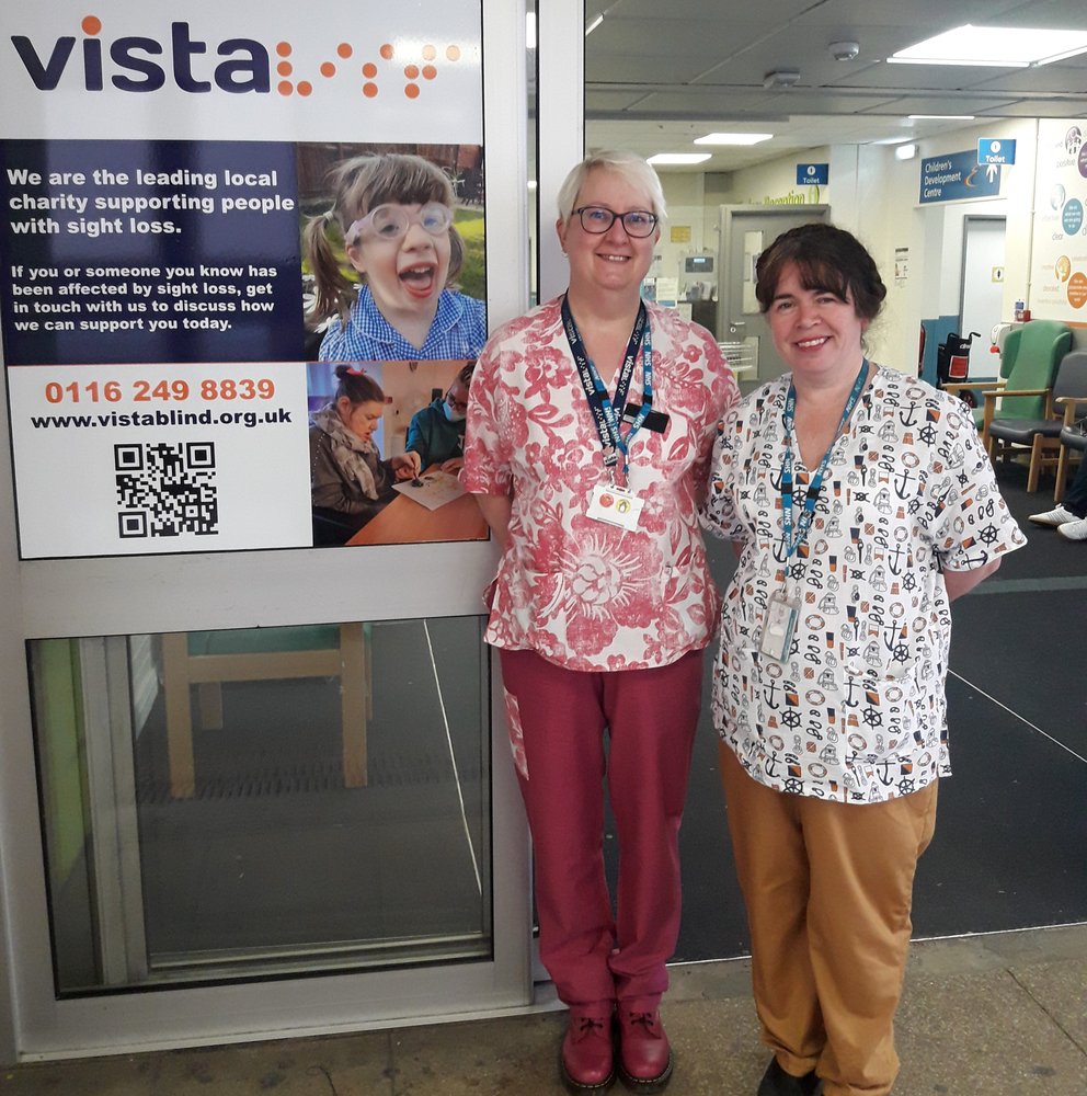 A picture of a two ladies stood at a vista sign in the hospital