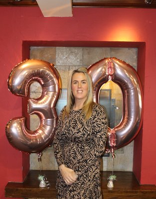 Emma standing next to '30' balloons