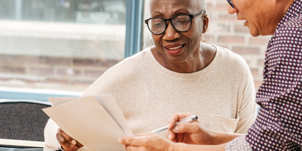 [Image Description: A man sits talking through a piece of paper with a woman who is smiling.]