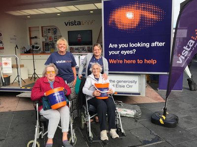 Two women in wheelchairs holding Vista buckets
