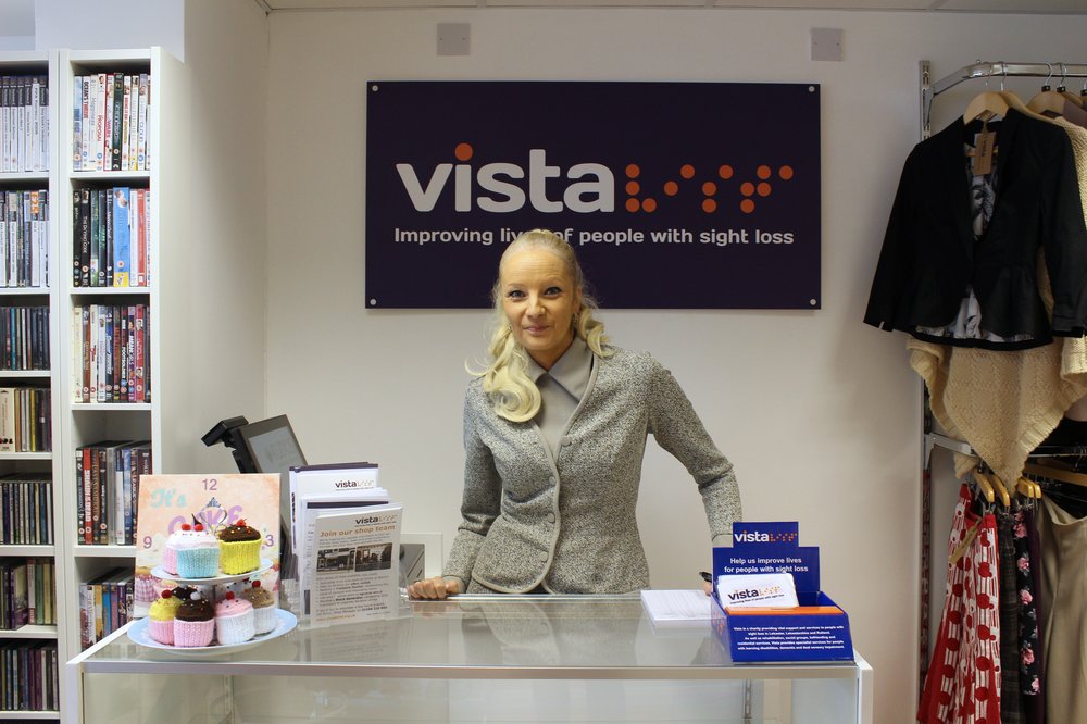 A picture of shop manager Penny Bailey smiling and stood at the shop till.