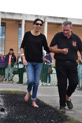 A lady walking across fire at Loughborough University at Vista's firewalk in 2022 and she is smiling.