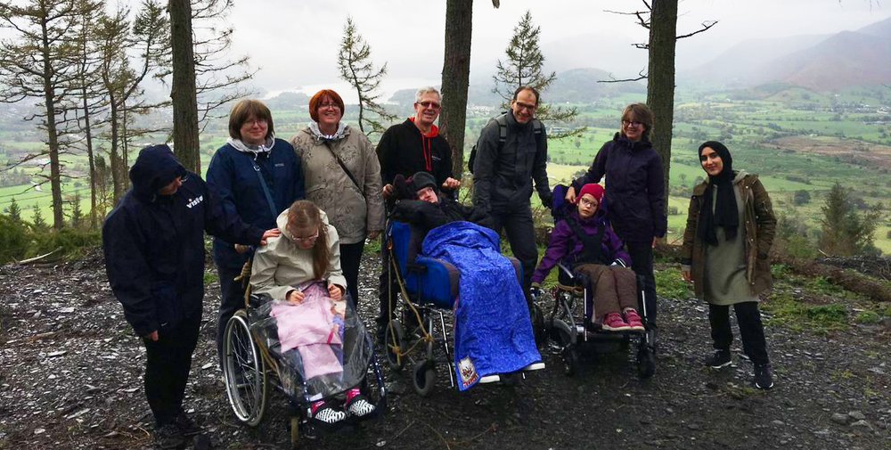 A picture of children and young people in a group photo atop a misty hill