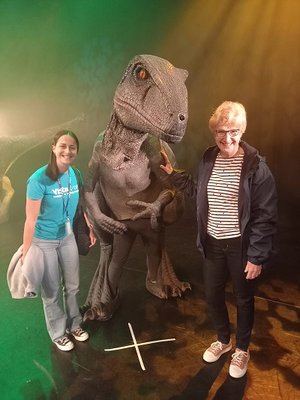 Rebecca and Jean standing next to a model dinosaur as part of an activity for Vista's Children and Young People. They are both smiling.
