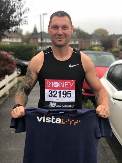 A runner running the virtual London Marathon last year and holding a Vista t-shirt.