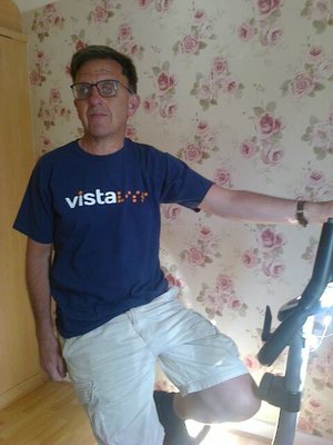 Image is of Chris Hammond wearing a Vista t-shirt sitting on an exercise bike.