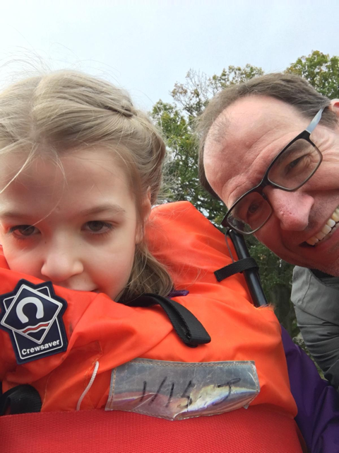 Image is of a girl and their guardian on a boat smiling