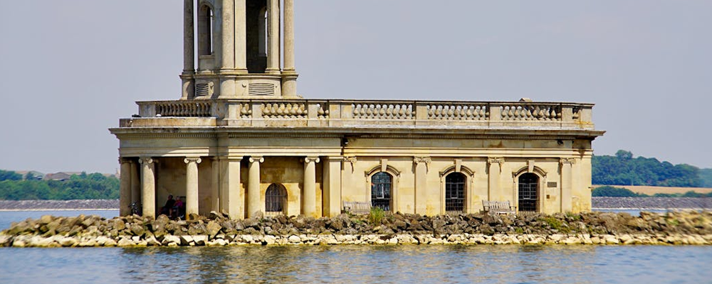 [Image Description: An image of the concrete building and tower at Rutland Water, surrounded by the lake with trees and buildings visible in the background.]