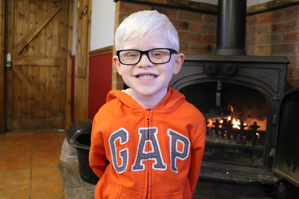 A picture of Shain stood in front of a fireplace.