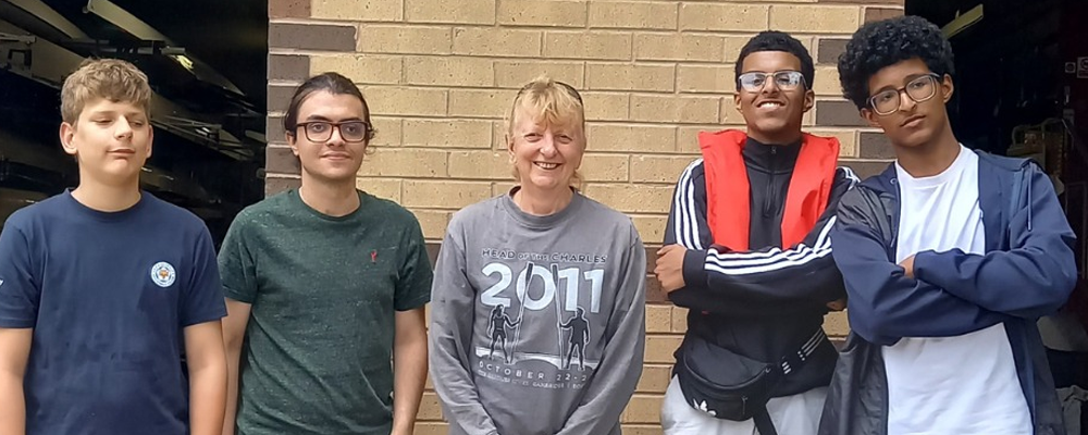 [Image Description: Five people, including four young people and one adult coach, standing outside Leicester Rowing Club under the club sign.]