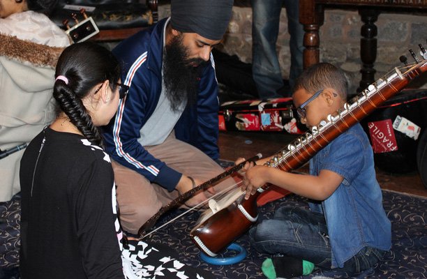 A picture of two children being taught how to play an instrument.