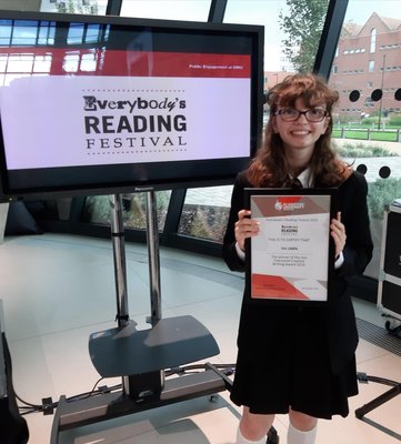 Isis holding her award, dressed in her school uniform