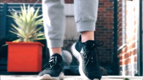 Image is of a close-up of someone taking a step and wearing trainers.